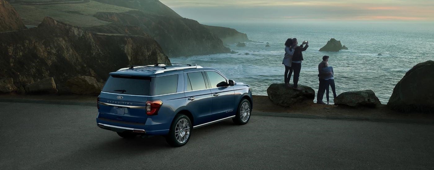 Rear of a blue 2023 Ford Expedition parked in front of a lake.