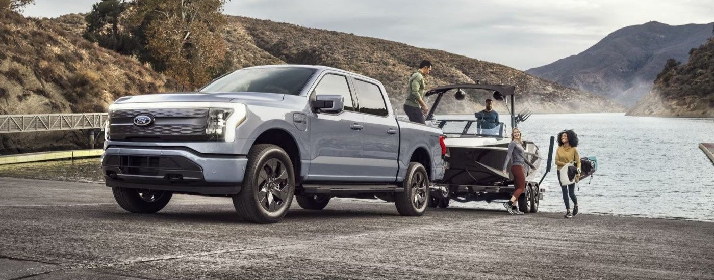 Grey 2023 Ford F-150 lightning towing a boat out of a lake