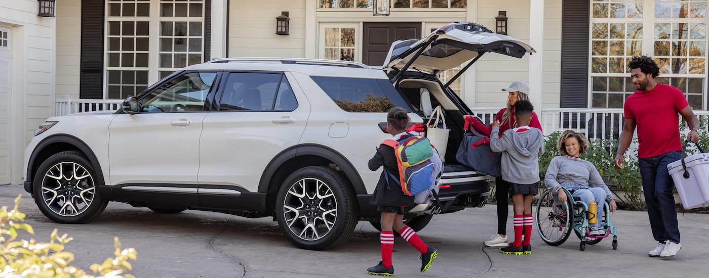 Family in sport gear near a white 2025 Ford Explorer