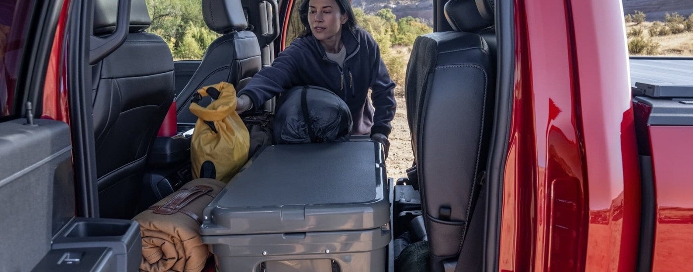 Person loading gear into the rear of a red 2025 Ford F-150