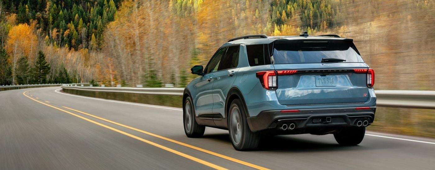 Blue 2026 Ford Explorer rear view driving on a road.