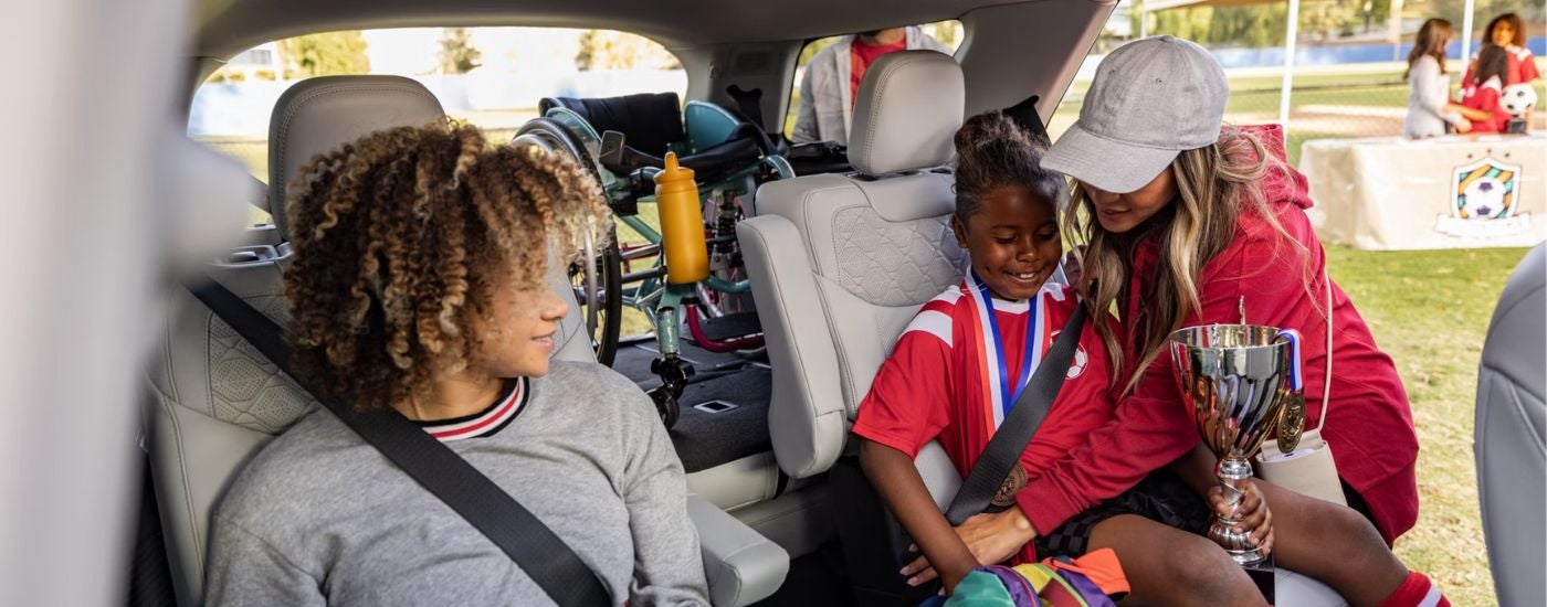 2026 Ford Explorer with a mom buckling kids in the rear seats and a loaded cargo area.