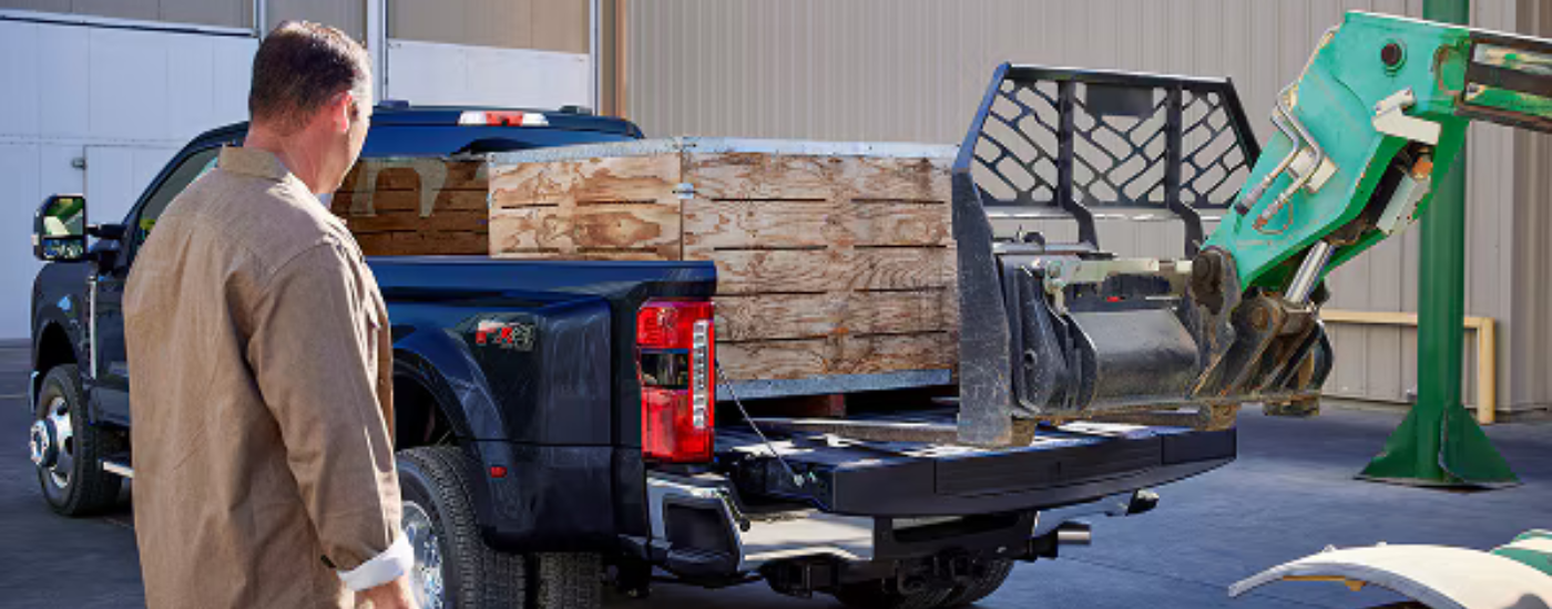 Black 2026 Ford F-350 with the bed being loaded with a crate