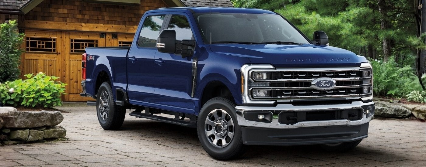 Dark blue 2026 Ford F-350 Super Duty parked on a driveway in front of a cabin.