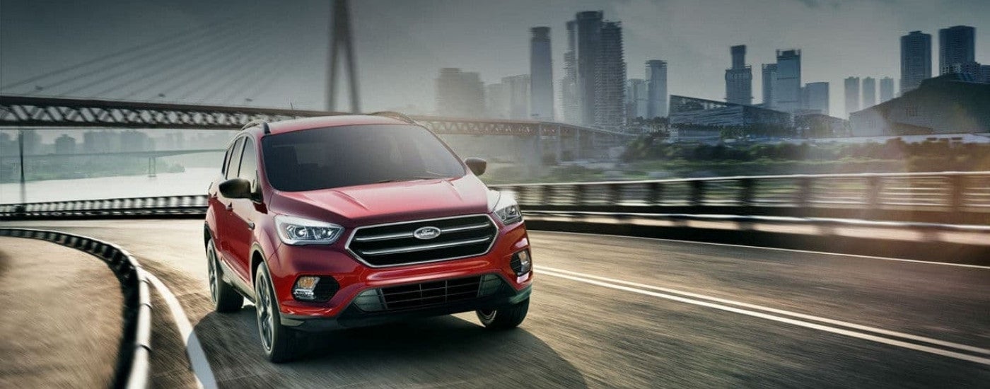 A red 2017 Ford Escape driving past a bridge.