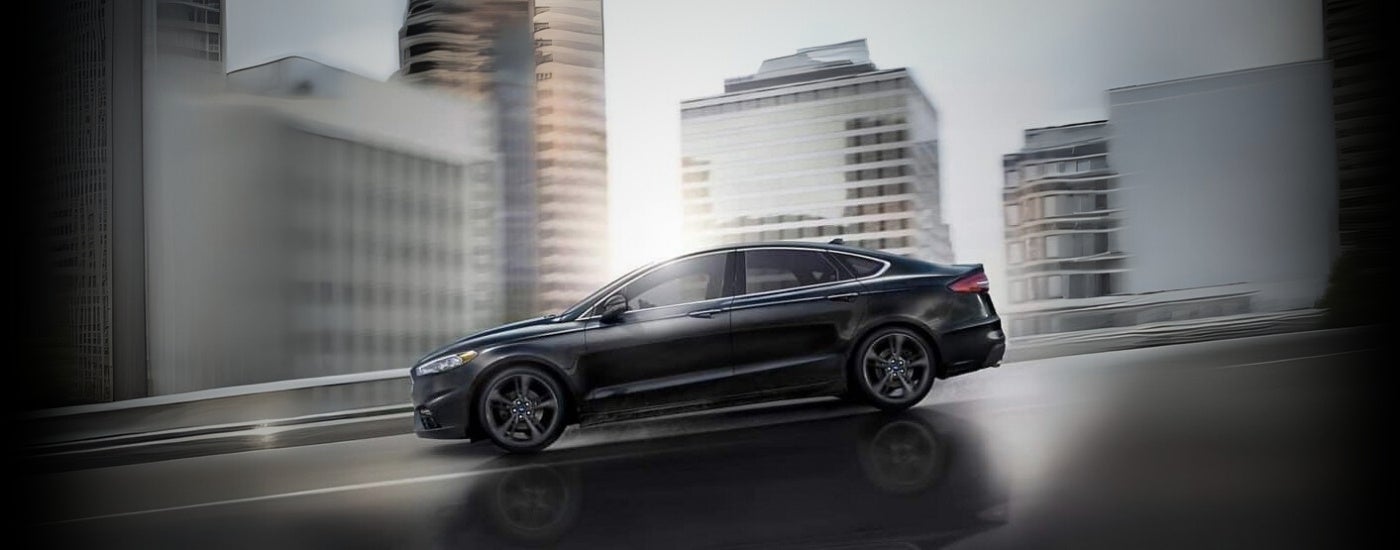 A black 2019 Ford Fusion driving on a city street.