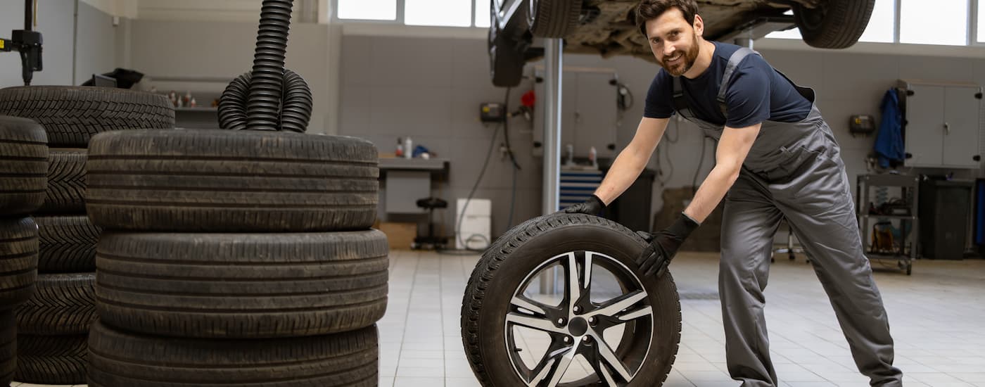 Service worker rolling a tire in a garage.